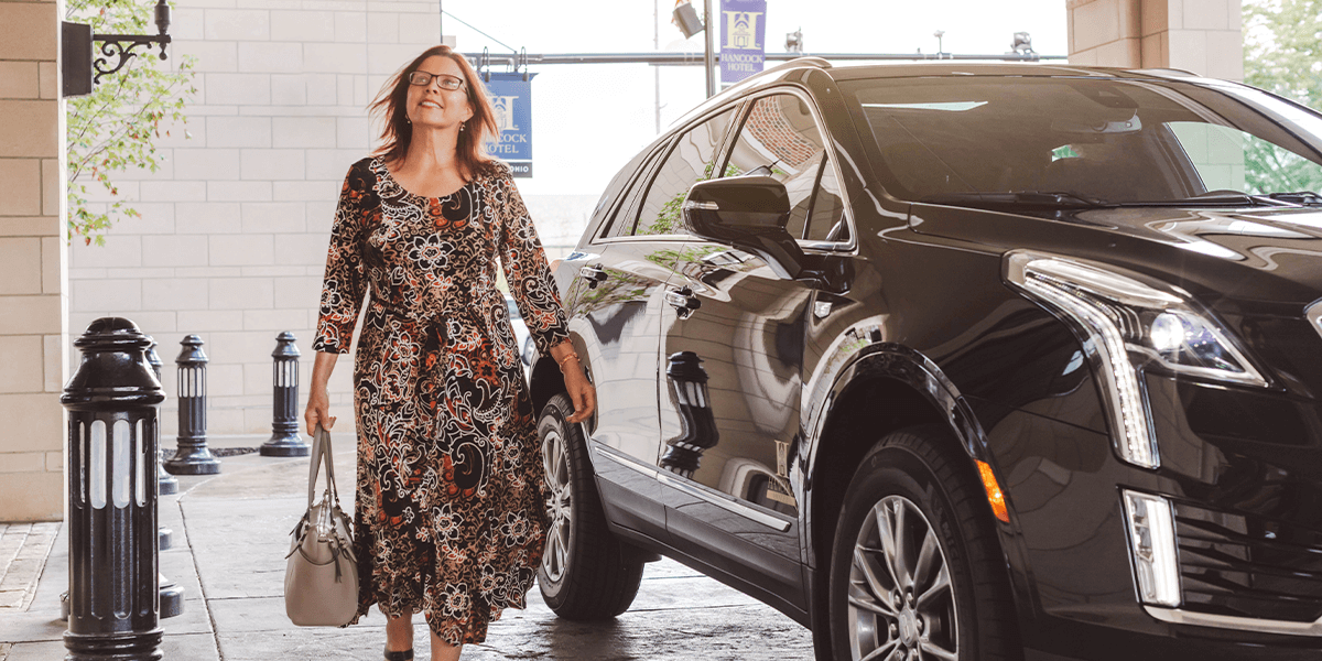 woman getting out of black car in a hotel drop off lane for valet